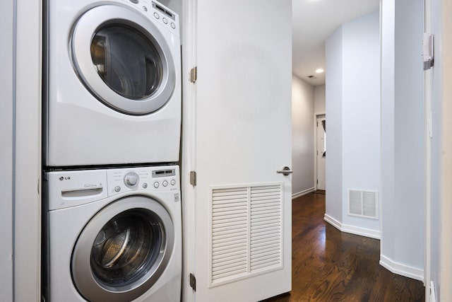 clothes washing area featuring stacked washer / dryer, dark wood finished floors, recessed lighting, and baseboards