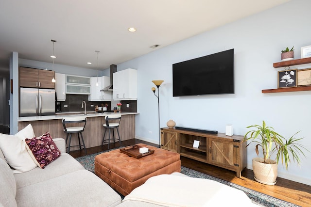 living room featuring dark wood finished floors, baseboards, and recessed lighting