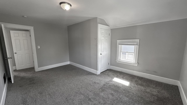 bonus room featuring dark colored carpet and baseboards