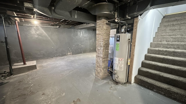 unfinished basement featuring water heater and stairway