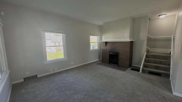unfurnished living room featuring a brick fireplace, stairway, carpet, and baseboards