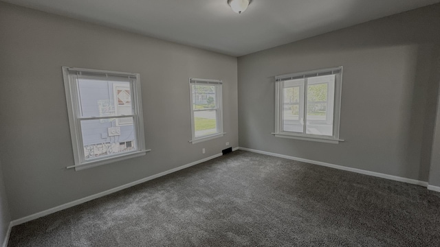 unfurnished room with dark carpet and baseboards