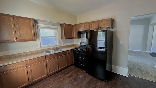 kitchen with black appliances, a sink, brown cabinetry, dark wood finished floors, and light countertops