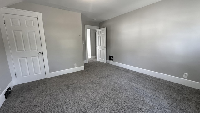 unfurnished bedroom featuring dark colored carpet and baseboards