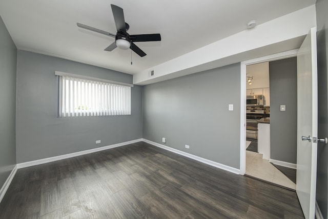empty room with a ceiling fan, wood finished floors, and baseboards