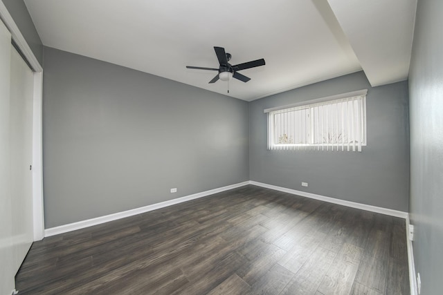 spare room featuring a ceiling fan, dark wood-style floors, and baseboards