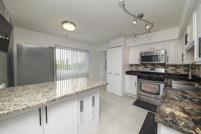 kitchen with appliances with stainless steel finishes, a sink, tasteful backsplash, and white cabinets