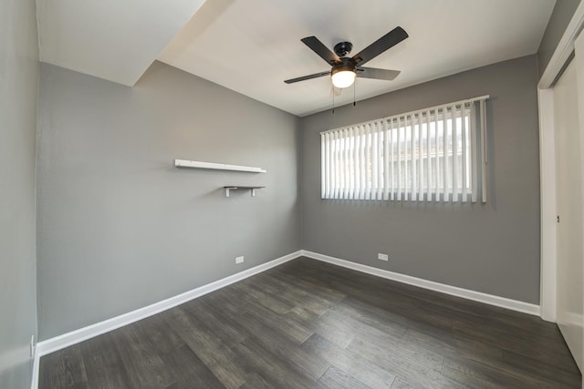 spare room featuring a ceiling fan, dark wood-style flooring, and baseboards