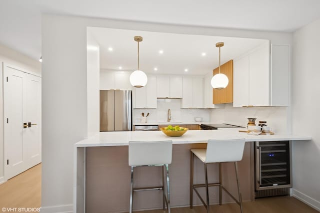 1560 N Sandburg Ter Unit 411J, Chicago, IL 60610 - kitchen featuring appliances with stainless steel finishes, wine cooler, a peninsula, a sink, and light wood-style floors