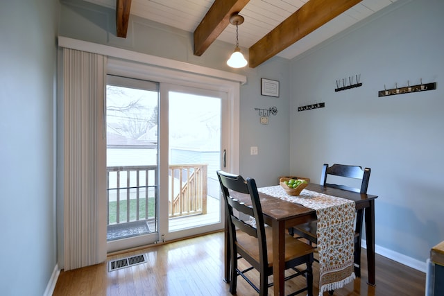 dining area with beam ceiling, wood finished floors, baseboards, and wooden ceiling