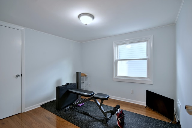 exercise room featuring wood finished floors, ornamental molding, and baseboards