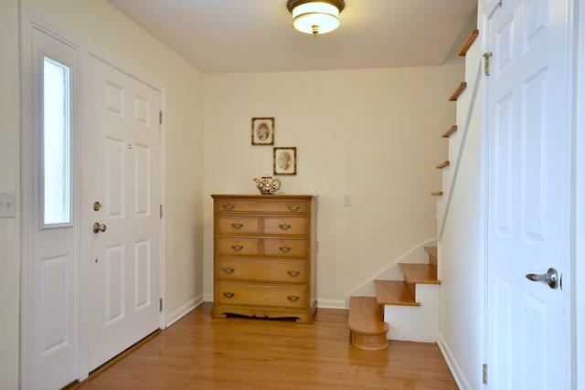 entrance foyer featuring stairs, light wood finished floors, baseboards, and plenty of natural light