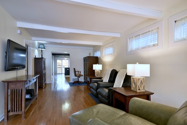 living area featuring beam ceiling, wood finished floors, and baseboards