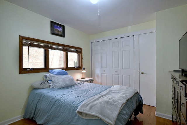 bedroom with wood finished floors, a closet, and baseboards
