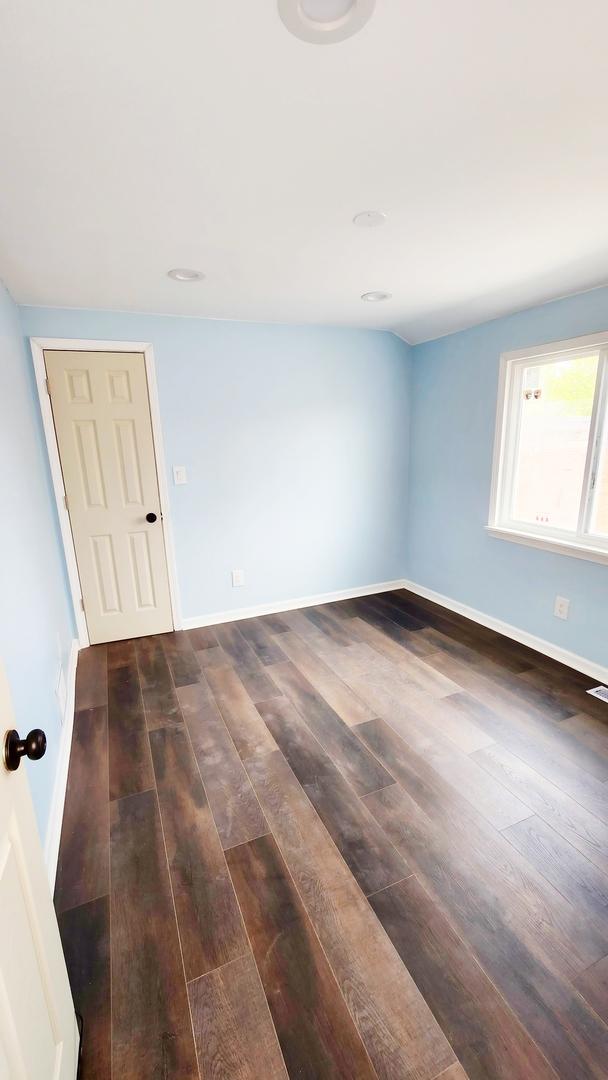 spare room with dark wood-type flooring and baseboards