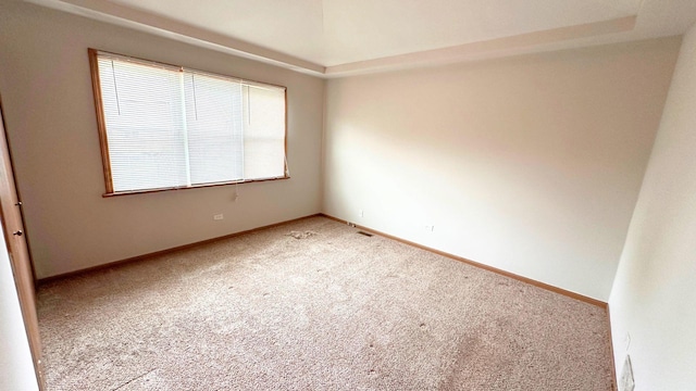 spare room featuring light carpet and baseboards