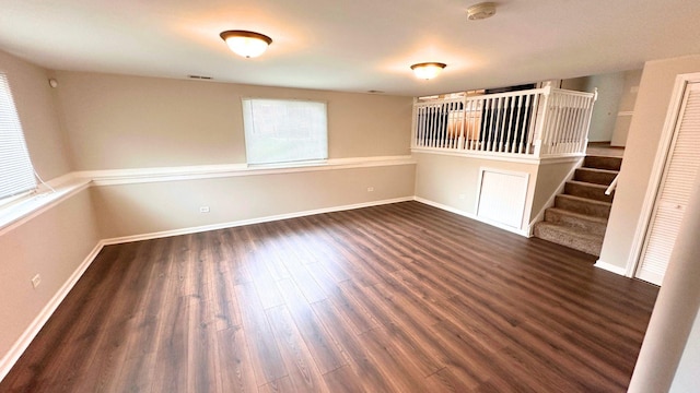 unfurnished room with wood finished floors, a smoke detector, stairway, and baseboards