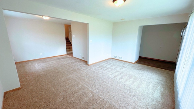 unfurnished room with stairway, carpet floors, and baseboards