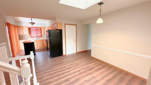 kitchen featuring freestanding refrigerator, light countertops, a skylight, and light wood-style floors
