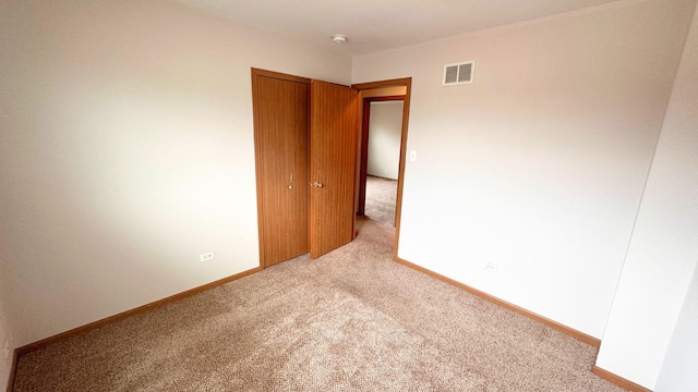 spare room featuring light colored carpet, baseboards, and a smoke detector