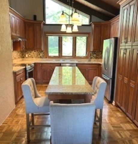 23105 N High Ridge Rd, Barrington, IL 60010 - kitchen featuring appliances with stainless steel finishes, a chandelier, a kitchen island, decorative backsplash, and brown cabinets