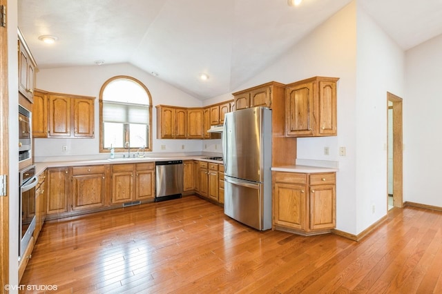 296 Regina Ln, Belvidere, IL 61008 - kitchen with appliances with stainless steel finishes, vaulted ceiling, light countertops, brown cabinetry, and light wood-style flooring