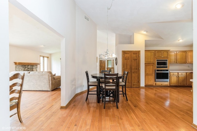 296 Regina Ln, Belvidere, IL 61008 - dining room with light wood-style floors, a chandelier, baseboards, and high vaulted ceiling
