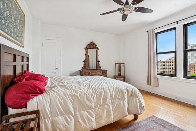 bedroom with ornamental molding, wood finished floors, baseboards, and a ceiling fan