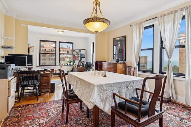 dining room featuring light wood finished floors, ornamental molding, and baseboards