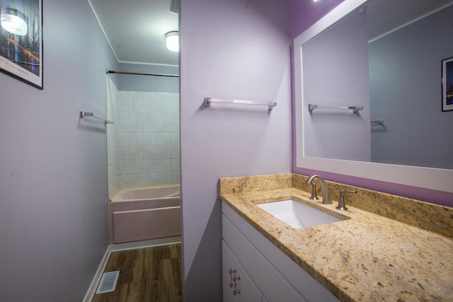 bathroom featuring wood finished floors, vanity, shower / tub combination, and ornamental molding