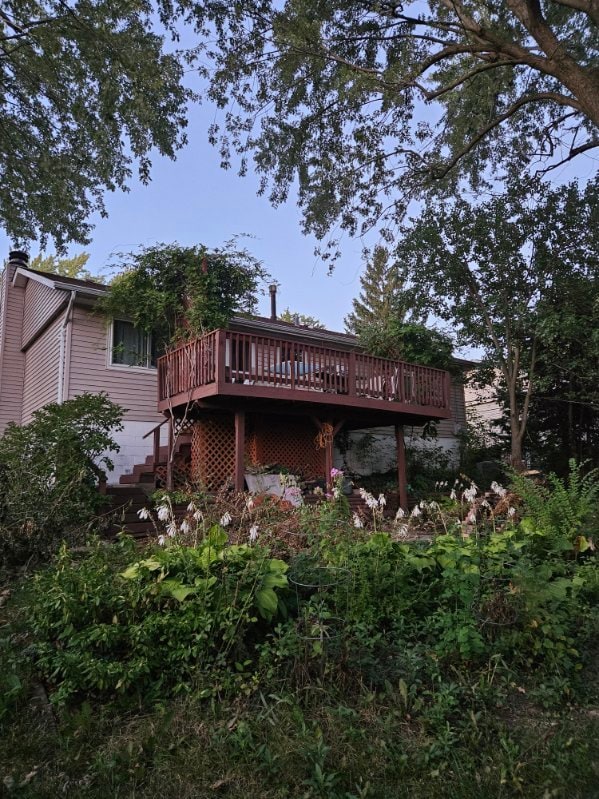 rear view of property with a wooden deck, a chimney, and stairs