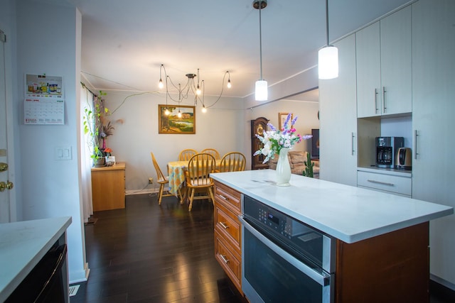 kitchen with oven, light countertops, dark wood-type flooring, and decorative light fixtures