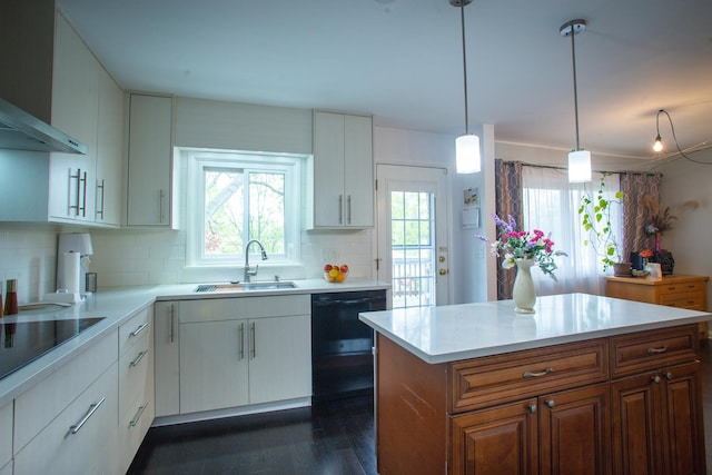 kitchen featuring a sink, wall chimney exhaust hood, healthy amount of natural light, and light countertops