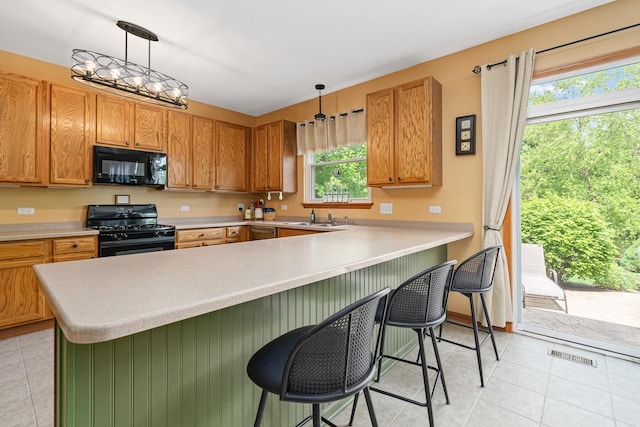 24210 Apple Creek Ln, Plainfield, IL 60586 - kitchen with black appliances, light tile patterned flooring, a sink, light countertops, and a breakfast bar area