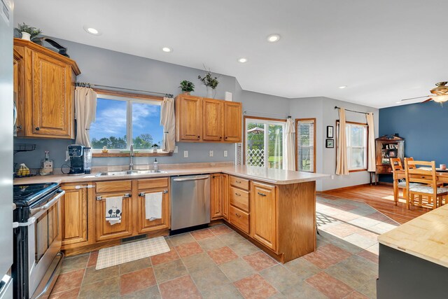 kitchen featuring stainless steel appliances, a sink, a peninsula, light countertops, and recessed lighting