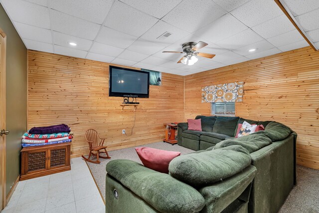 living room with wooden walls, a ceiling fan, a drop ceiling, and recessed lighting