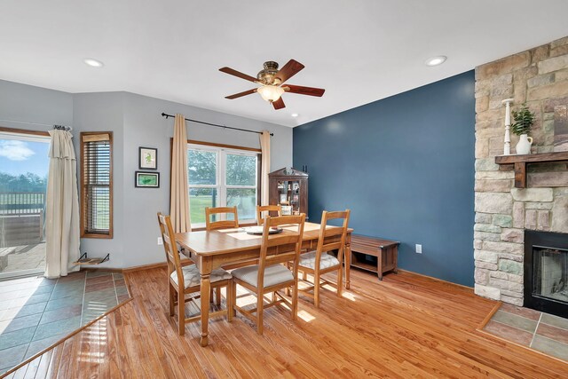 dining space featuring a ceiling fan, light wood finished floors, a fireplace, baseboards, and recessed lighting
