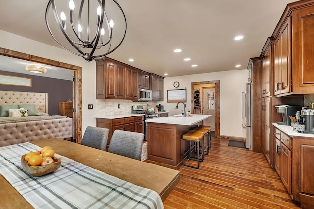 2588 Big Bluestem Rd, Morris, IL 60450 - kitchen with stainless steel appliances, wood finished floors, an island with sink, light countertops, and tasteful backsplash
