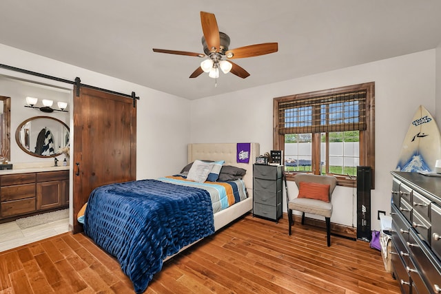 2588 Big Bluestem Rd, Morris, IL 60450 - bedroom featuring light wood-style floors, a barn door, ensuite bathroom, and a ceiling fan