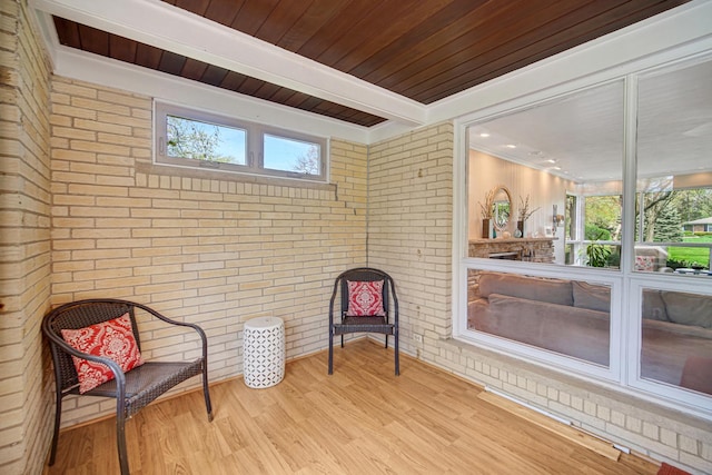 sitting room featuring brick wall, wood finished floors, beamed ceiling, and wood ceiling