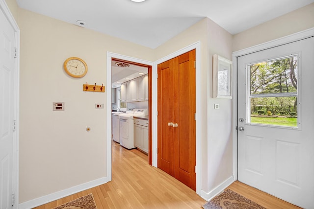 entryway with washer / dryer, baseboards, and light wood-style flooring