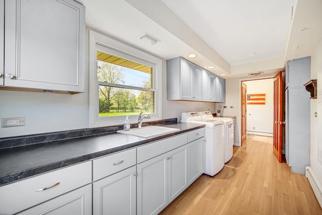 kitchen with a sink, washing machine and clothes dryer, dark countertops, light wood finished floors, and recessed lighting