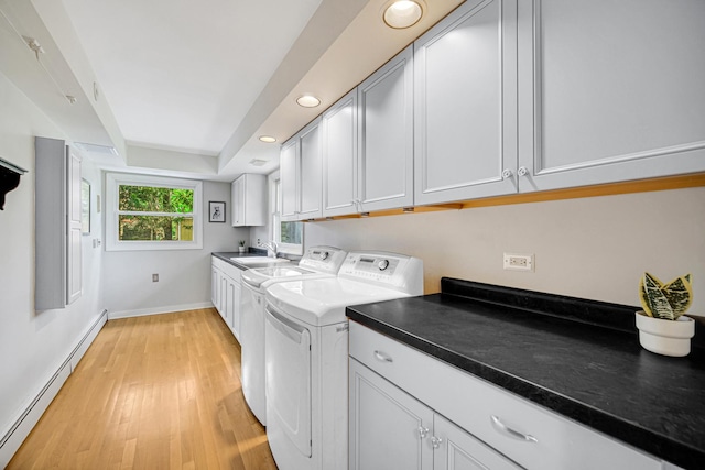 washroom with baseboard heating, cabinet space, washer and dryer, light wood-style floors, and baseboards
