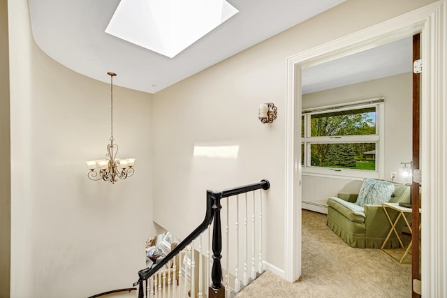corridor featuring an upstairs landing, carpet floors, a baseboard heating unit, a skylight, and a chandelier