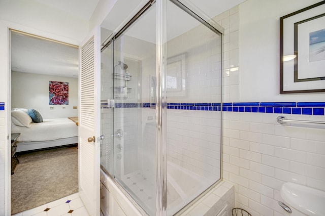 bathroom featuring ensuite bathroom, toilet, a stall shower, tile walls, and tile patterned floors