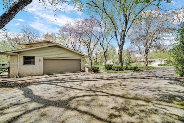 view of property exterior featuring brick siding, driveway, and an attached garage