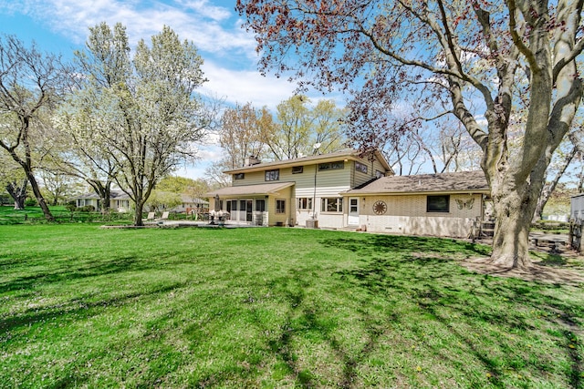 rear view of house with a yard, brick siding, and a patio area