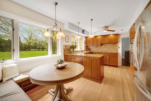kitchen with freestanding refrigerator, brown cabinetry, healthy amount of natural light, and light wood finished floors