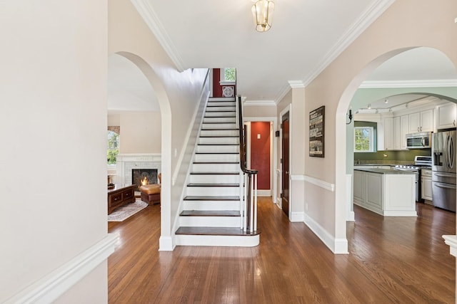 2141 Evans Rd, Flossmoor, IL 60422 - staircase featuring wood finished floors, crown molding, a warm lit fireplace, baseboards, and arched walkways
