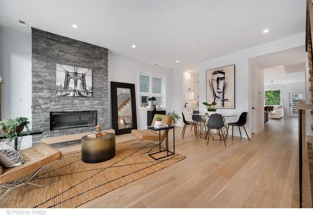 living room featuring recessed lighting, a stone fireplace, and wood finished floors